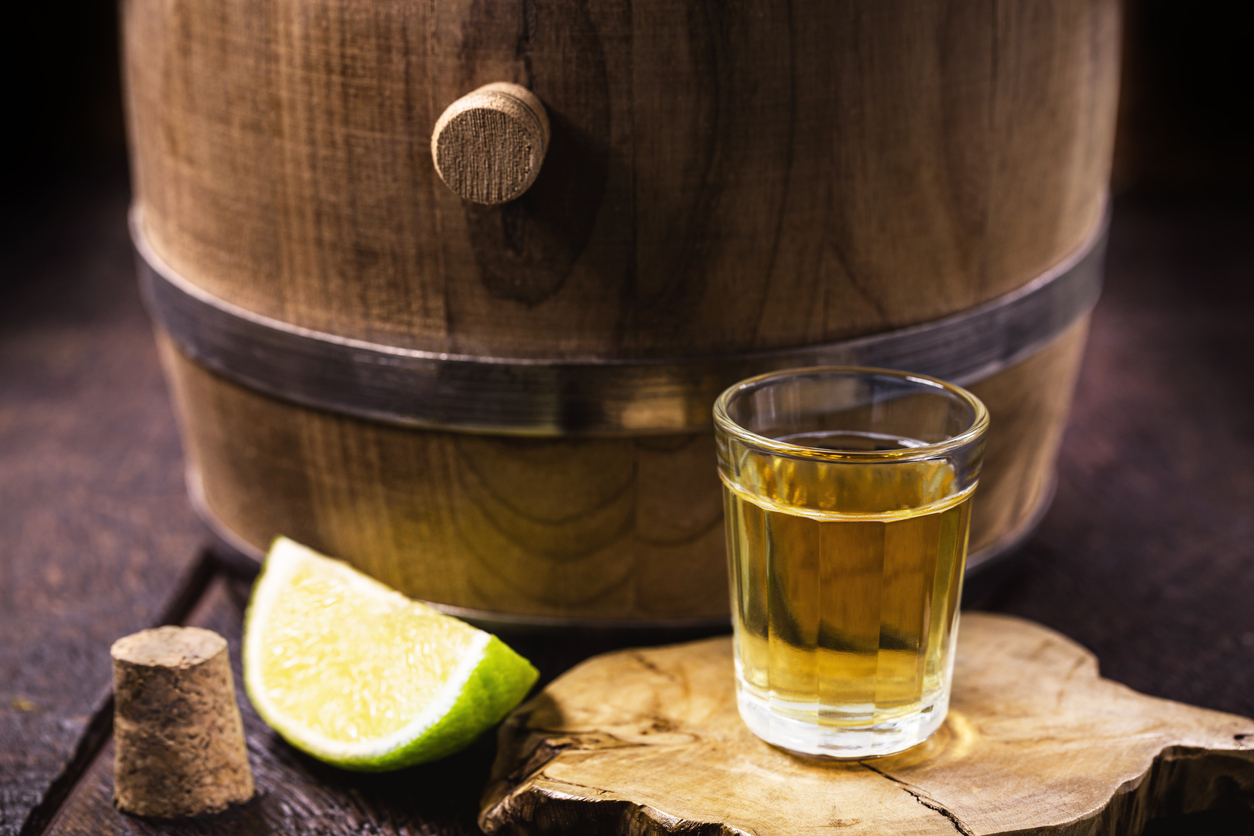 Cups of barrel aged tequila displayed on a rustic surface, emphasizing the premium quality and traditional aging process in oak barrels.